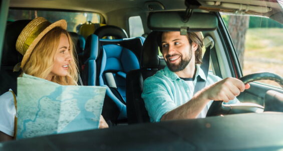 happy couple traveling by car with map